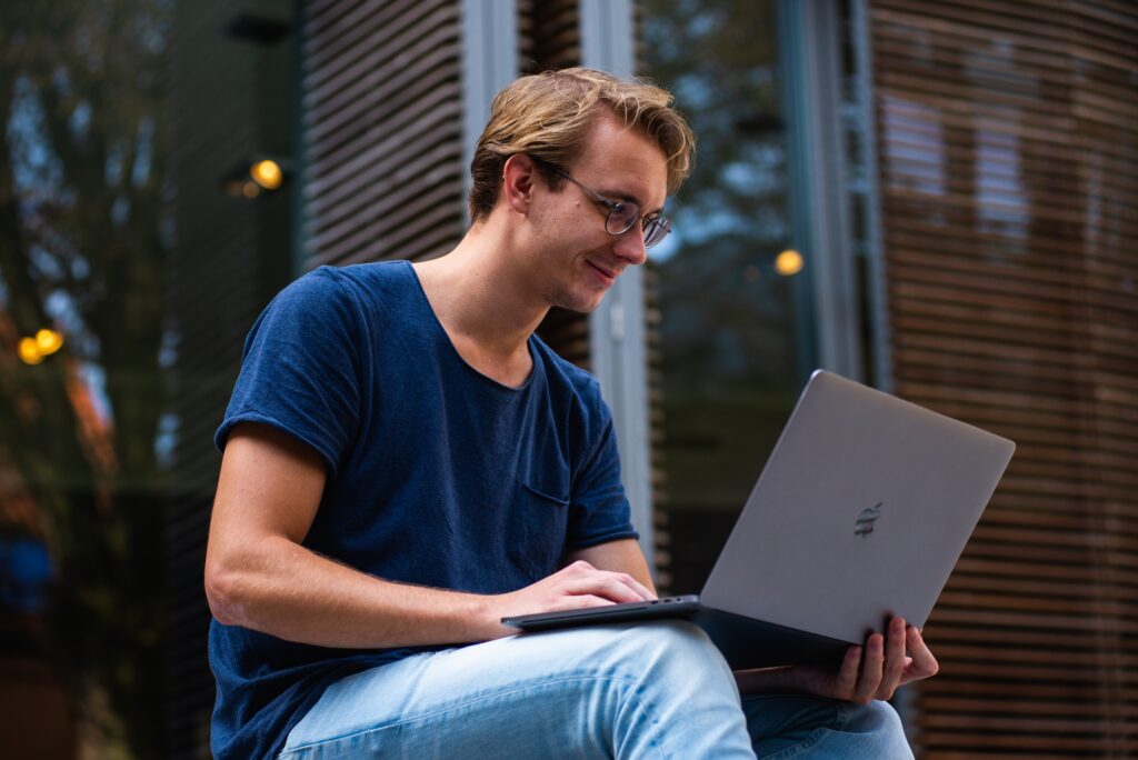 happy student taking up online college degree while holding laptop